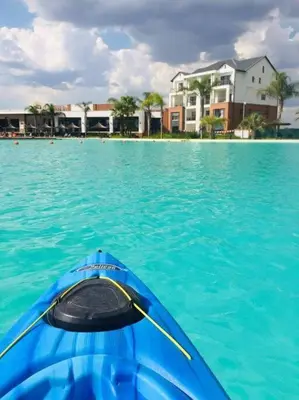 a kayak in the water in front of a house at Luxury beach lagoon 1 Bedroom apartment in Pretoria