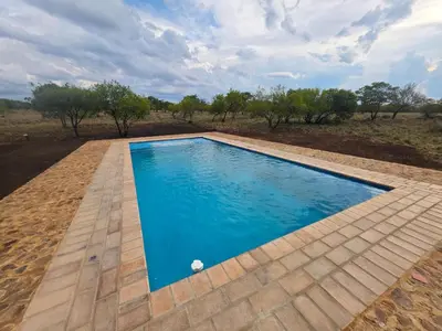 a swimming pool with a wooden floor and blue water at Klipdrift Sands Game Lodge in Dinokeng Game Reserve