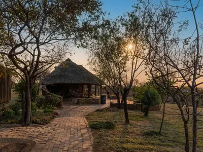 a pavilion in a park with trees and a brick path at Klipdrift Sands Game Lodge in Dinokeng Game Reserve