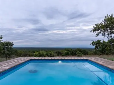 a swimming pool with a view of the ocean at Klipdrift Sands Game Lodge in Dinokeng Game Reserve