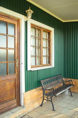 a bench sitting outside of a green house with a door at Machado Stay Pecan Cottage 1 in Machadodorp