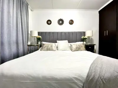 a bedroom with a large bed with white sheets and pillows at Siena Sun Luxury Suites 2 in Midrand