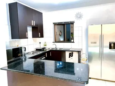 a kitchen with black countertops and a stainless steel refrigerator at Siena Sun Luxury Suites 2 in Midrand