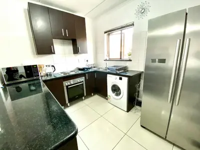 a kitchen with a refrigerator and a washing machine at Siena Sun Luxury Suites 2 in Midrand