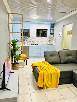 a living room with a couch and a yellow blanket at Modern studio apartments in Secunda