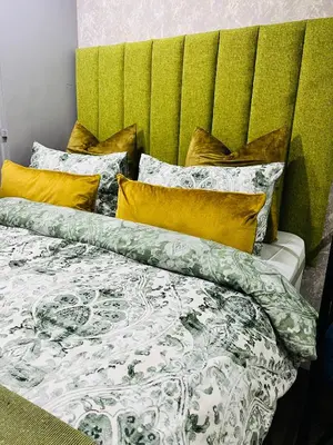 a bed with green and white sheets and yellow pillows at Modern studio apartments in Secunda