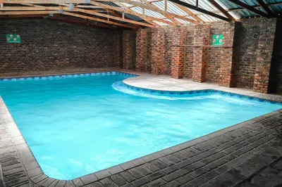 a large swimming pool with a brick wall and blue water at Lodge Laske Nakke in Lydenburg