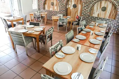 a dining room with a long wooden table and chairs at Lodge Laske Nakke in Lydenburg