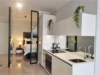 a kitchen with white cabinets and a bed in a room at Executive Suite at Ellipse Waterfall Midrand in Midrand