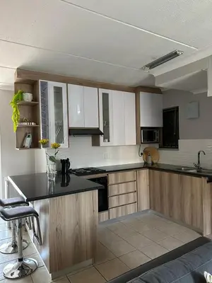 a kitchen with wooden cabinets and a black counter top at Air bnb 204 in Midrand