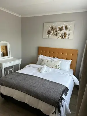 a bedroom with a large white bed and a table at Air bnb 204 in Midrand