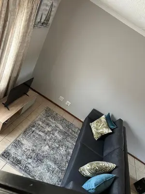 a living room with a black couch with pillows at Air bnb 204 in Midrand