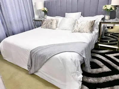 a bedroom with a bed with white sheets and pillows at Siena Sun Luxury Suites 5 in Midrand