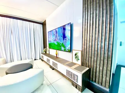 a living room with a white couch and a tv at Midrand Siena Sun Luxury Suites 3 with water reserve in Midrand