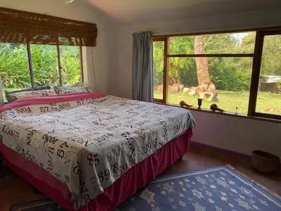 a bedroom with a bed and a large window at Thathe Dam Lodge in Vhutandabos