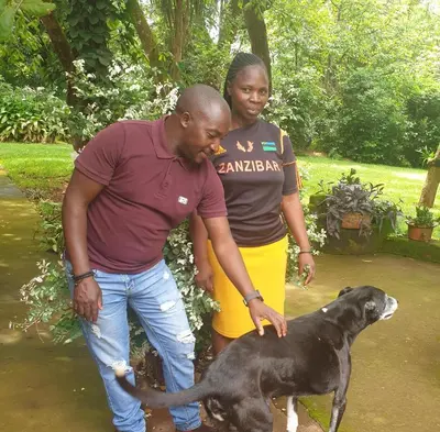 a man and woman standing next to a black dog at Thathe Dam Lodge in Vhutandabos