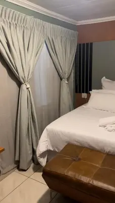 a bedroom with a bed and a window with curtains at Silverton Private Apartment in Pretoria