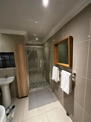 a bathroom with a shower and a toilet and a sink at Silverton Private Apartment in Pretoria