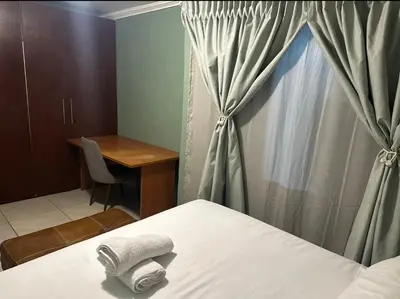 a bedroom with a bed and a desk and a window at Silverton Private Apartment in Pretoria