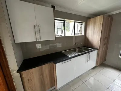 a small kitchen with white cabinets and a sink at Silverton Private Apartment in Pretoria