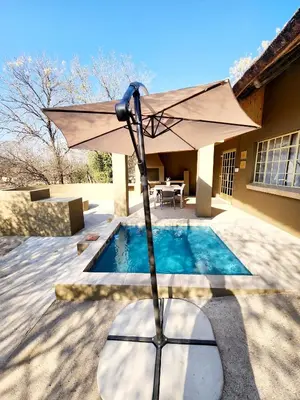 a white umbrella sitting next to a swimming pool at Kudus Crest Bush Retreat in Marloth Park