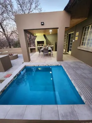 a swimming pool in front of a house at Kudus Crest Bush Retreat in Marloth Park
