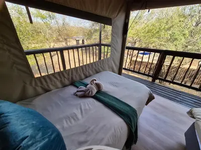a teddy bear laying on a bed in a tent at Kudus Crest Bush Retreat in Marloth Park
