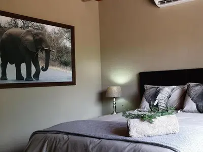 a bedroom with a picture of an elephant on the wall at Kudus Crest Bush Retreat in Marloth Park