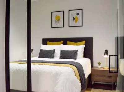 a bedroom with a large bed with yellow and white pillows at iNqaba @Ellipse Waterfall in Midrand