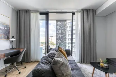 a living room with a couch and a large window at iNqaba @Ellipse Waterfall in Midrand