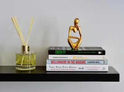 a stack of books sitting on a shelf with a statue at iNqaba @Ellipse Waterfall in Midrand