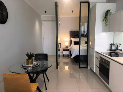 a kitchen and living room with a table and a bed at Executive Suite at Ellipse in Waterfall Midrand in Midrand