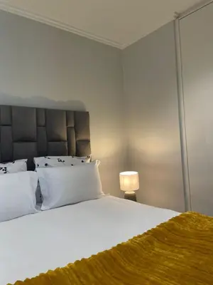 a bedroom with a large white bed and a lamp at Executive Suite at Ellipse in Waterfall Midrand in Midrand