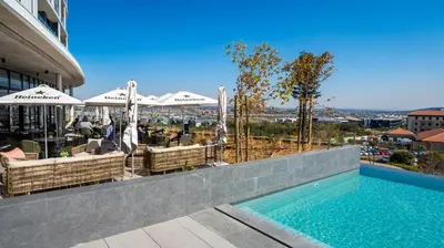 a swimming pool with tables and umbrellas on a building at Executive Suite at Ellipse in Waterfall Midrand in Midrand