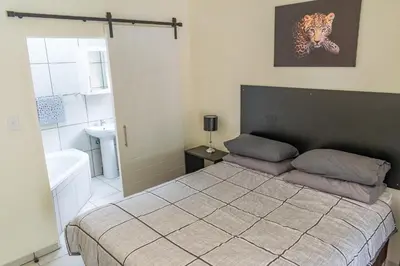 a bedroom with a large bed and a bathroom at Ingwe House in Marloth Park