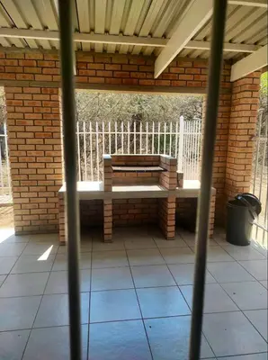 a bench sitting on a patio under a brick wall at Ingwe House in Marloth Park