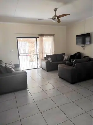 a living room with couches and a ceiling fan at Ingwe House in Marloth Park