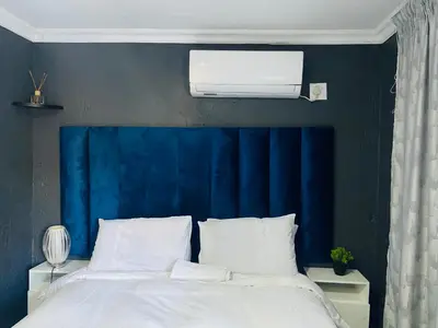 a bedroom with a blue headboard and a white bed at Executive Galaxy Guest House Nkowankowa Extension 2 in Tzaneen
