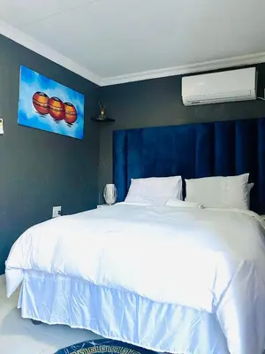 a white bed in a bedroom with a blue wall at Executive Galaxy Guest House Nkowankowa Extension 2 in Tzaneen