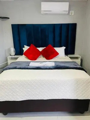 a bed with two red pillows on top of it at Executive Galaxy Guest House Nkowankowa Extension 2 in Tzaneen