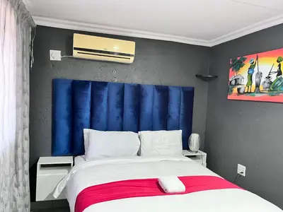 a bedroom with a large bed with a blue headboard at Executive Galaxy Guest House Nkowankowa Extension 2 in Tzaneen