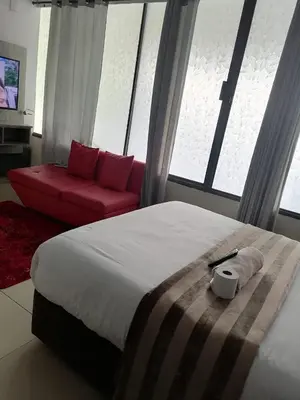 a bedroom with a large bed and a red couch at Tshilidzi Guest House in Pretoria