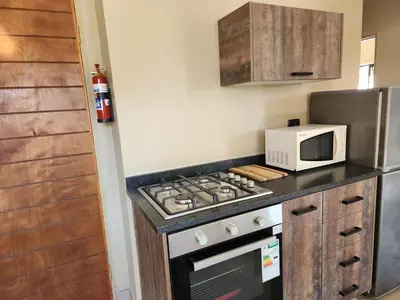a kitchen with a stove top oven next to a microwave at Lloyds - 6 in Ermelo