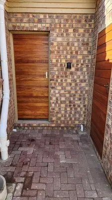 a brick building with a wooden door and a brick wall at Lloyds - 6 in Ermelo
