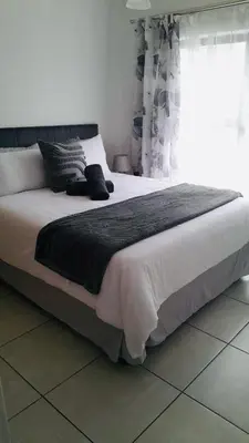 a large bed in a bedroom with a window at Joy Apartment@The Blyde in Pretoria
