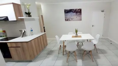 a kitchen with a white table and white chairs at Joy Apartment@The Blyde in Pretoria