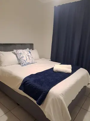 a bed with a blue blanket on top of it at Joy Apartment@The Blyde in Pretoria