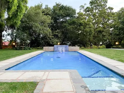a swimming pool in the middle of a yard at Afrique134 Baobab Tree Private Family Garden Suite in Pretoria