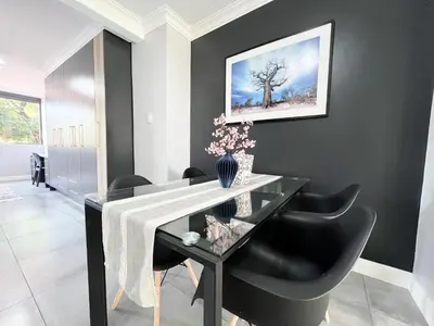 a dining room with a black table and black chairs at Afrique134 Baobab Tree Private Family Garden Suite in Pretoria