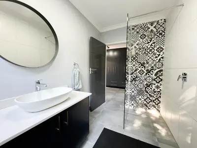 a bathroom with a sink and a shower with a mirror at Afrique134 Baobab Tree Private Family Garden Suite in Pretoria